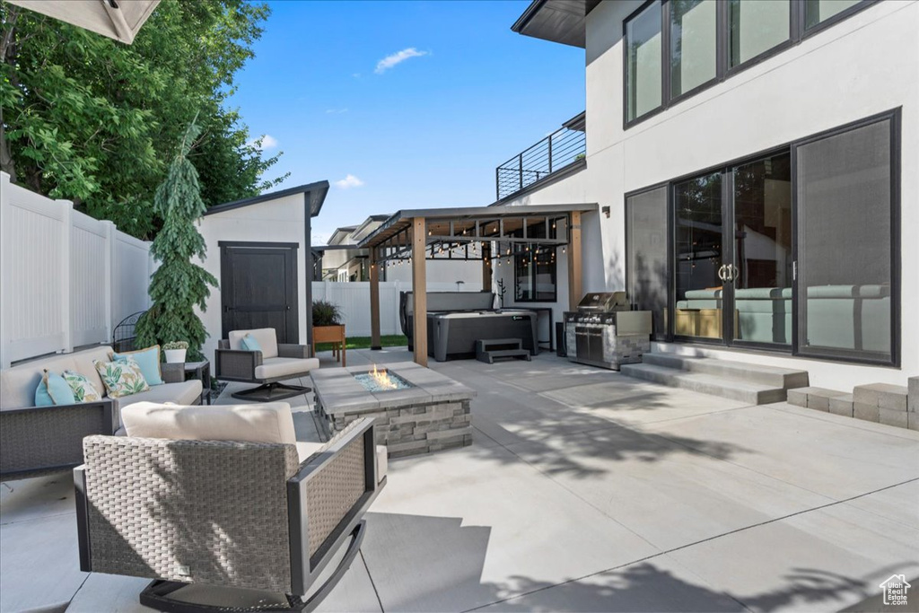 Patio / terrace featuring a hot tub, an outdoor living space with a fire pit, a patio, a fenced backyard, and a shed