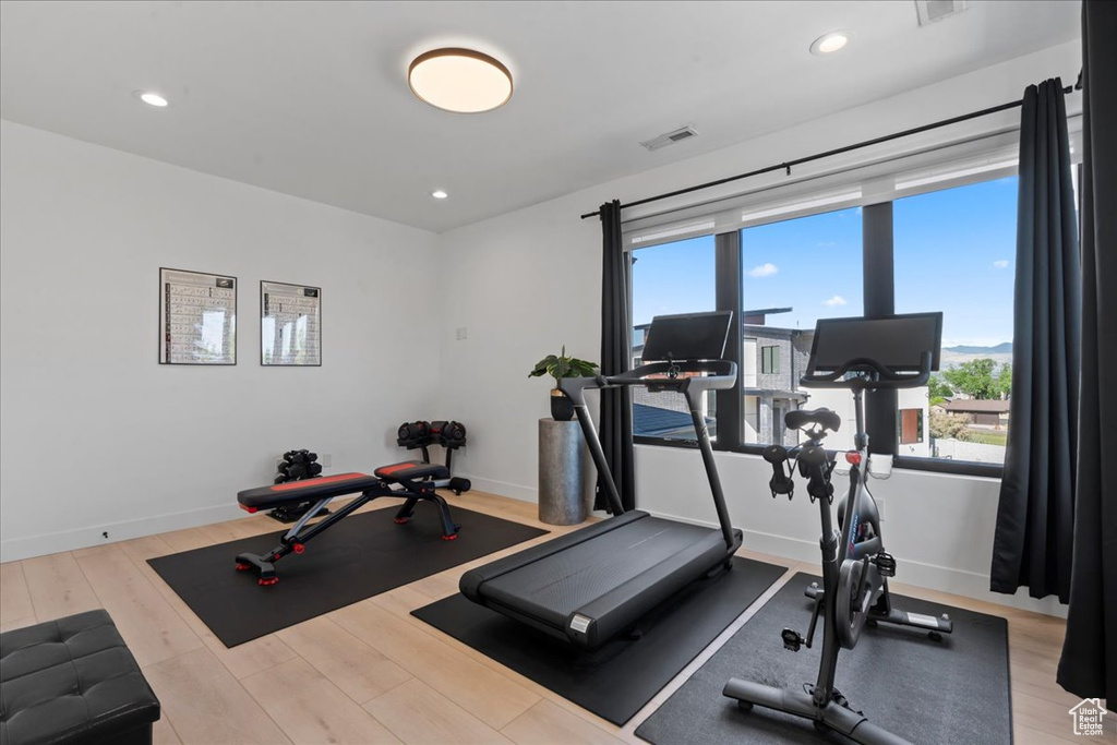 Exercise room with wood finished floors and recessed lighting