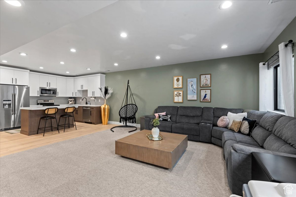 Living room with recessed lighting, light wood finished floors, and light carpet