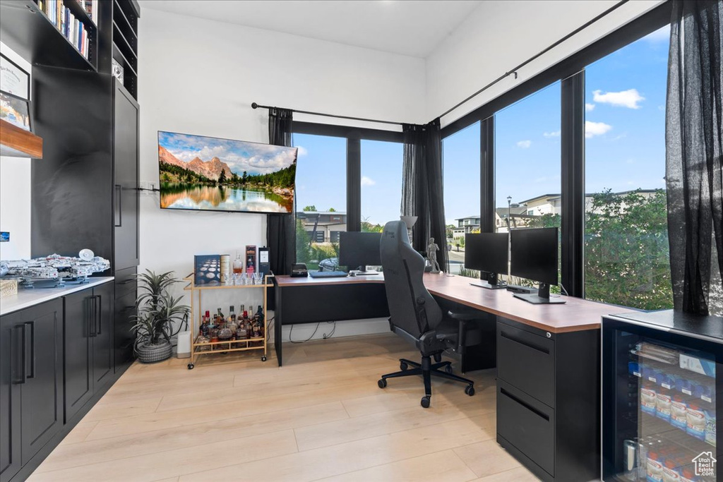 Office with beverage cooler, plenty of natural light, and light wood-style flooring