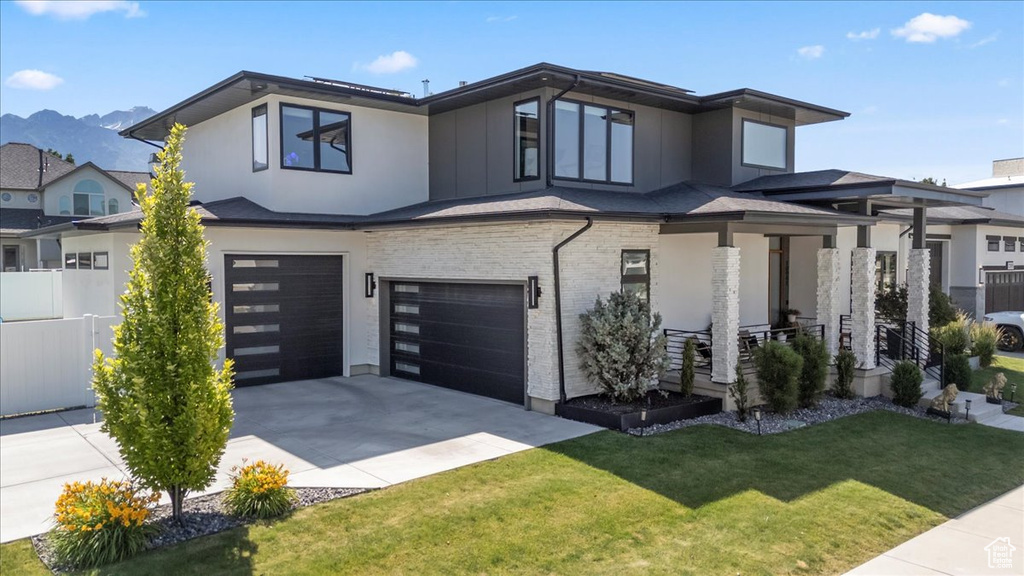 View of front of house with an attached garage, covered porch, concrete driveway, a mountain view, and brick siding