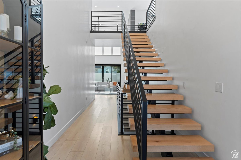 Stairs featuring a high ceiling and wood finished floors