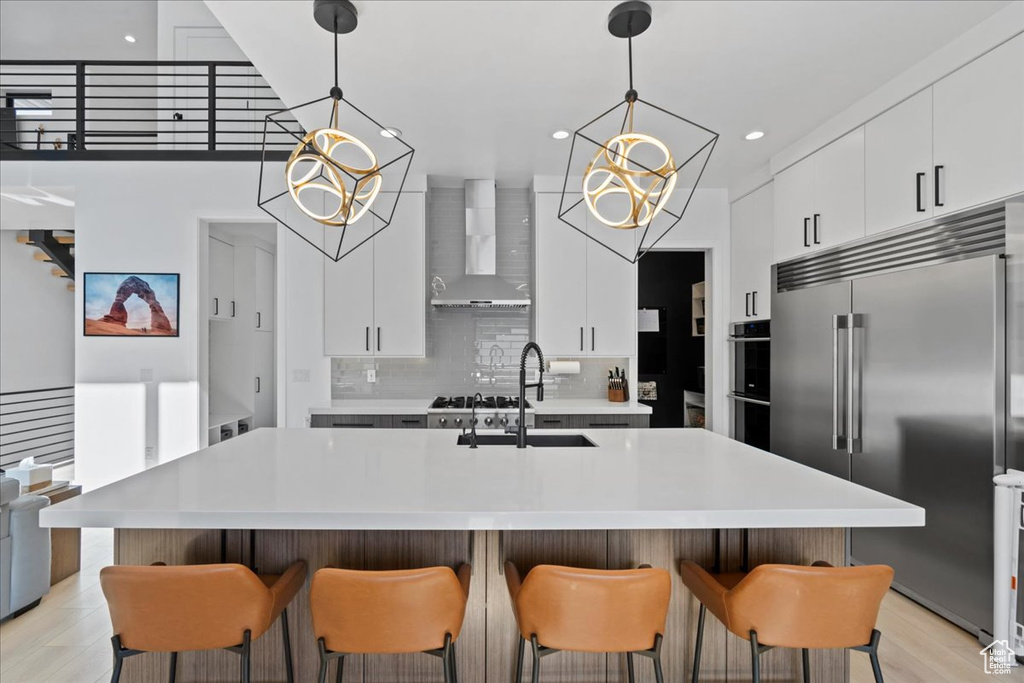 Kitchen with stainless steel appliances, wall chimney range hood, light countertops, tasteful backsplash, and recessed lighting