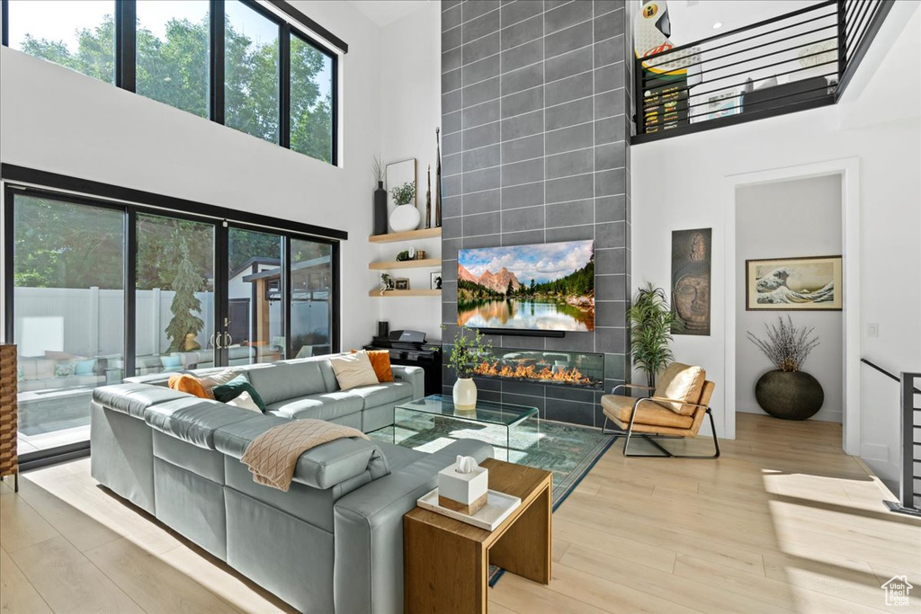 Living area with a towering ceiling, plenty of natural light, wood finished floors, and a tile fireplace