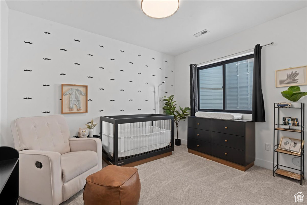 Bedroom featuring light colored carpet and a nursery area
