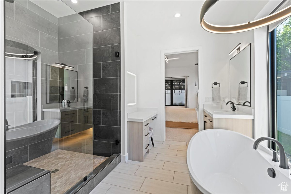 Ensuite bathroom featuring a stall shower, a freestanding tub, and vanity