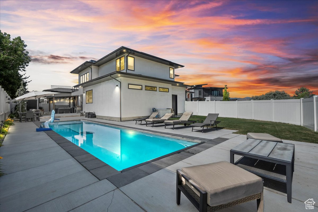 Pool at dusk featuring a fenced backyard, a patio area, and an outdoor living space