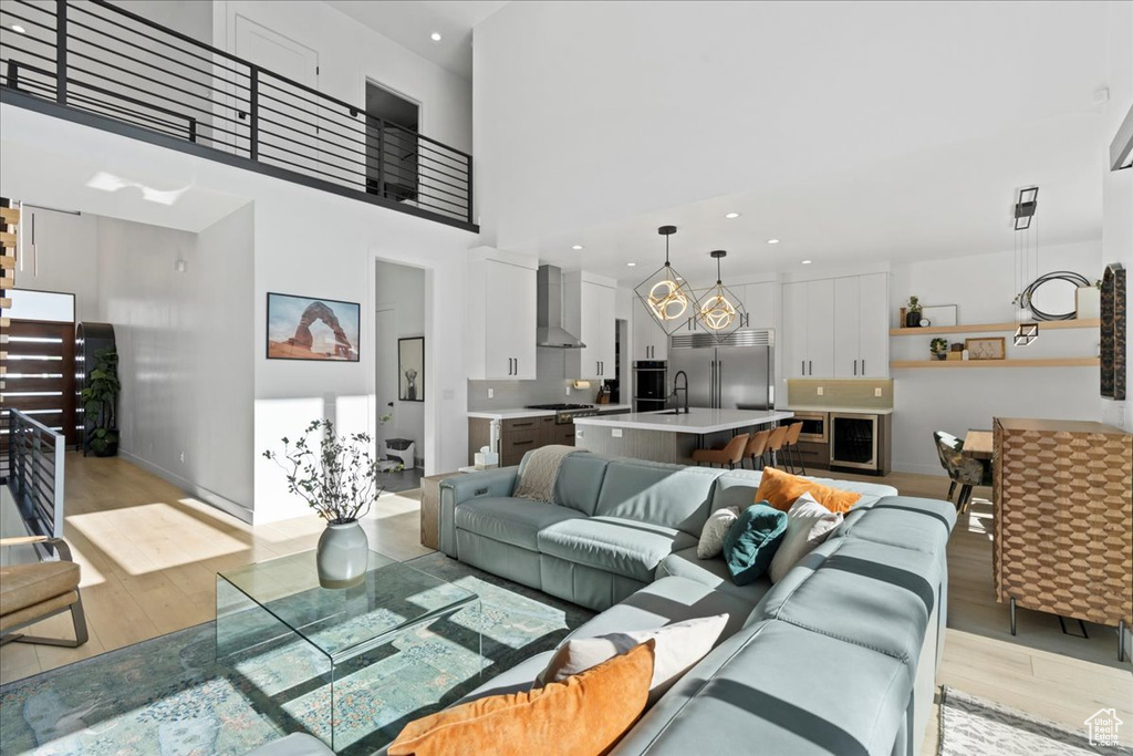Living area featuring light wood-type flooring, a high ceiling, and recessed lighting