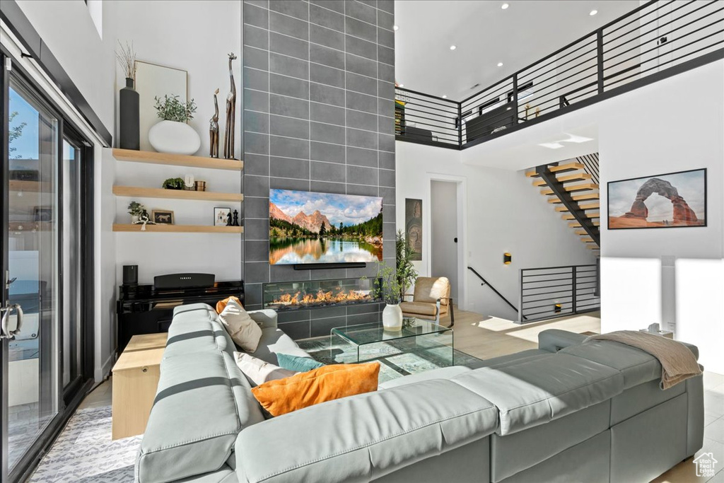 Living room with a towering ceiling, a tiled fireplace, and recessed lighting