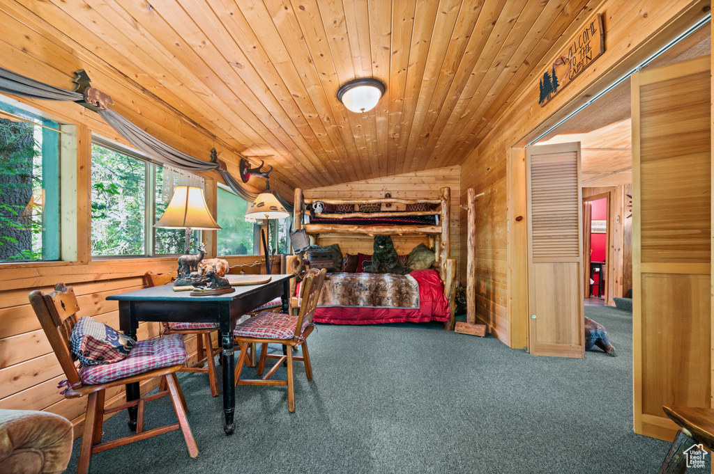 Dining room with wooden walls, vaulted ceiling, carpet, and wooden ceiling