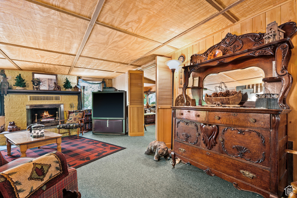 Carpeted living room with wood ceiling, wooden walls, and a fireplace