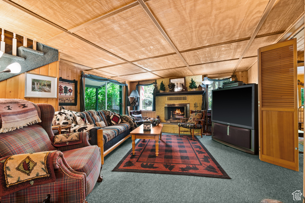 Carpeted living room with wooden walls, wood ceiling, and a fireplace