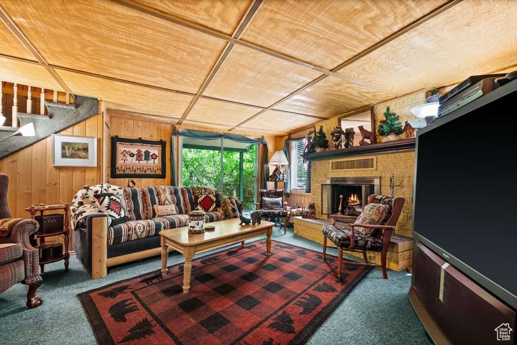 Living area with carpet, wooden walls, stairs, and a brick fireplace