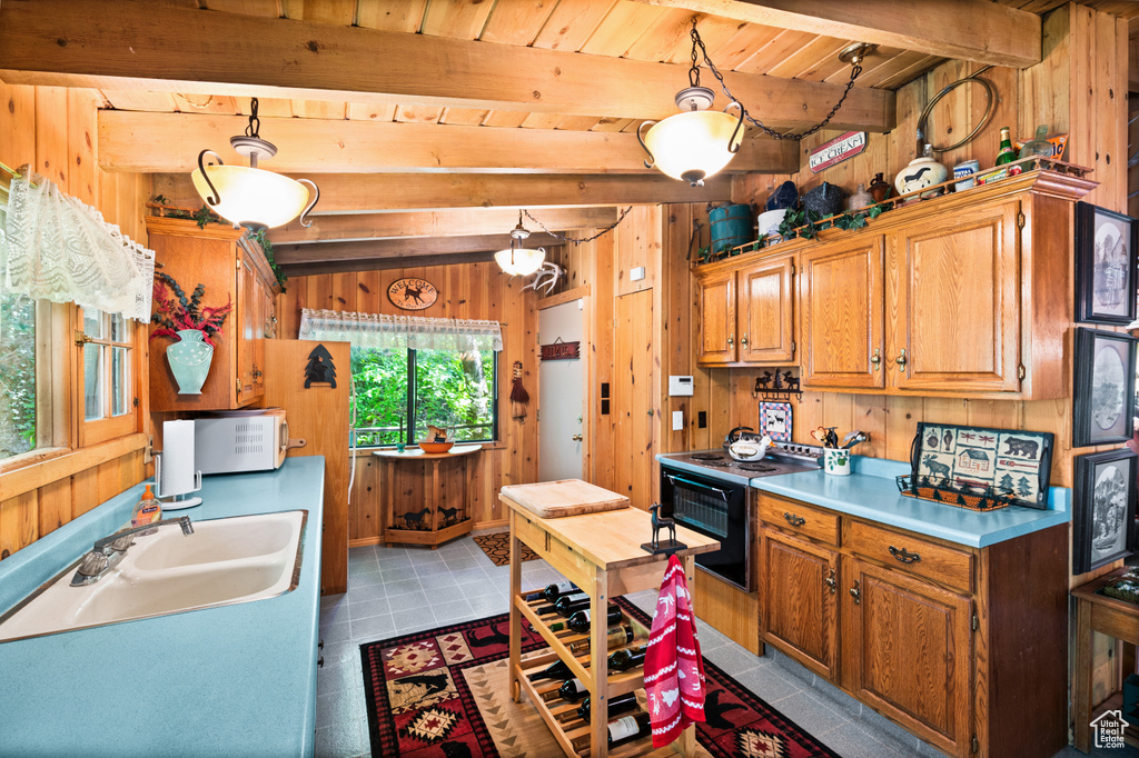 Kitchen with wooden walls, electric range, a wooden ceiling with exposed beams, brown cabinets, and light countertops