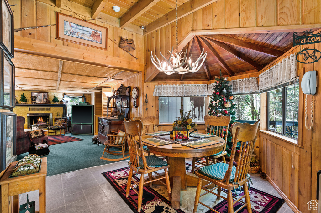 Dining space with wooden ceiling, wood walls, a chandelier, and a fireplace