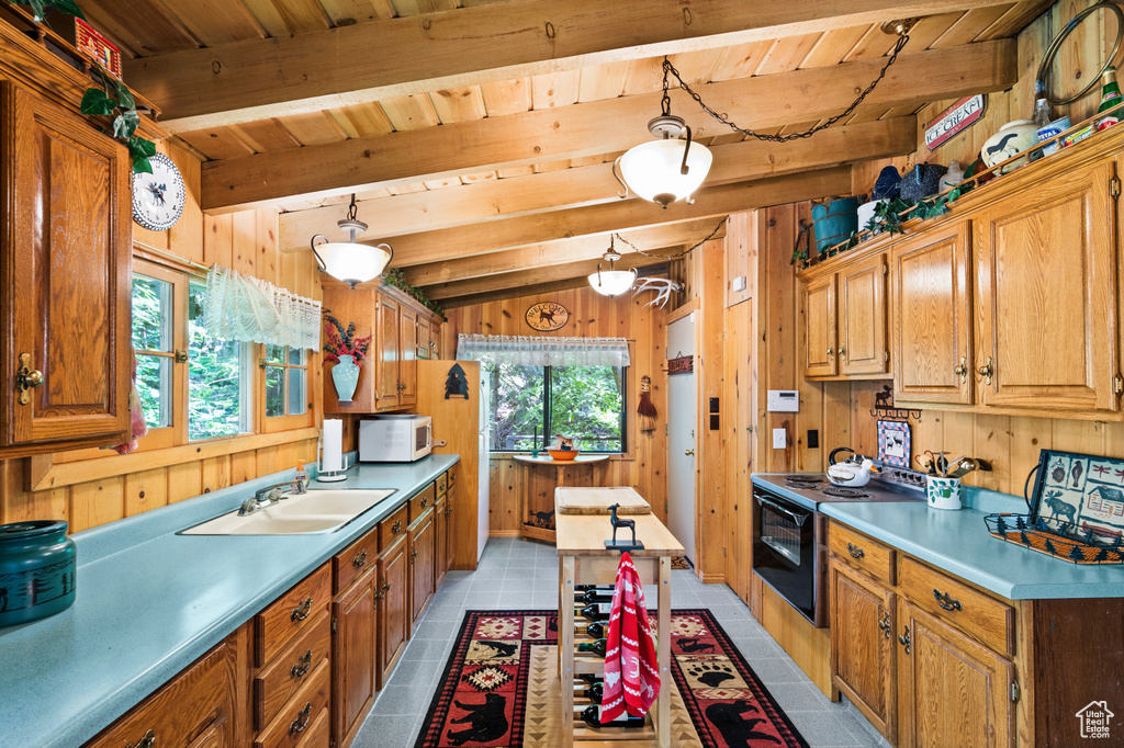 Kitchen with white microwave, black electric range oven, a wood ceiling with exposed beams, wooden walls, and light countertops