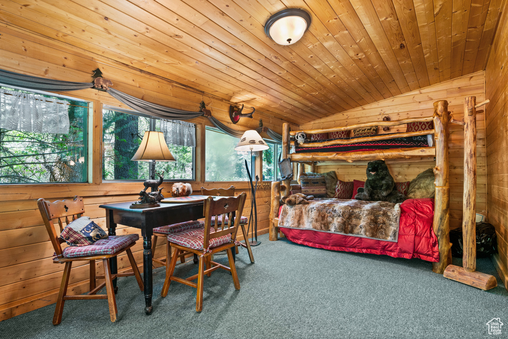 Carpeted dining room featuring lofted ceiling, wooden walls, and wood ceiling