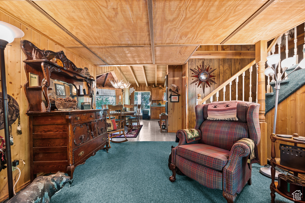 Sitting room featuring wooden walls, wood ceiling, stairway, and carpet floors