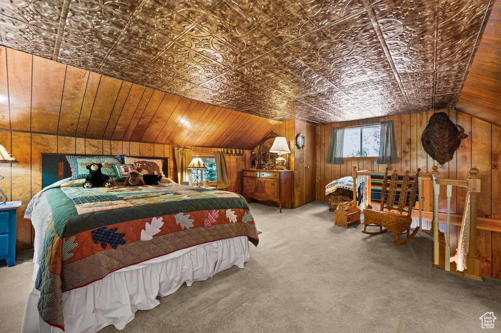 Carpeted bedroom with wooden walls, vaulted ceiling, and an ornate ceiling