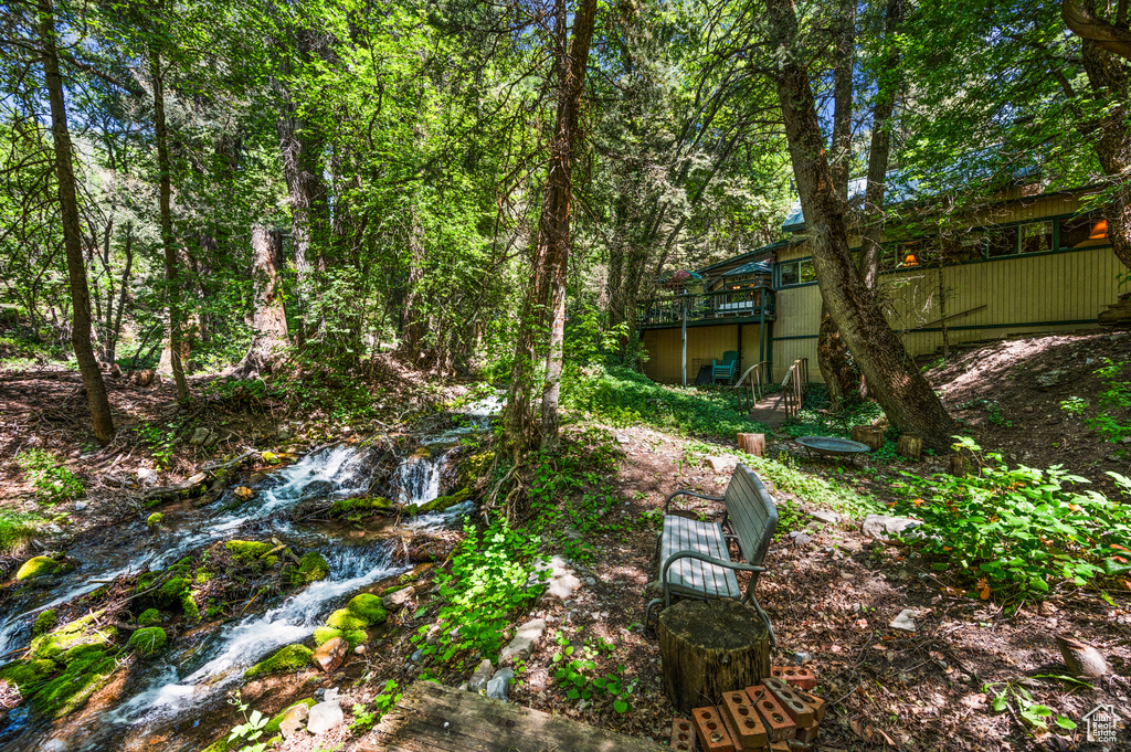 View of yard with a deck and a view of trees
