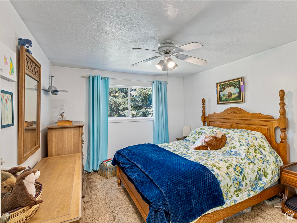 Bedroom featuring light colored carpet, a textured ceiling, and ceiling fan