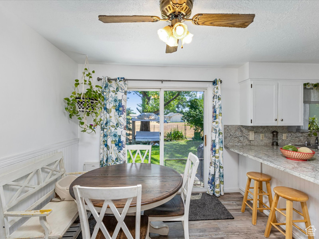 Dining room featuring light wood-style flooring, a ceiling fan, and a textured ceiling