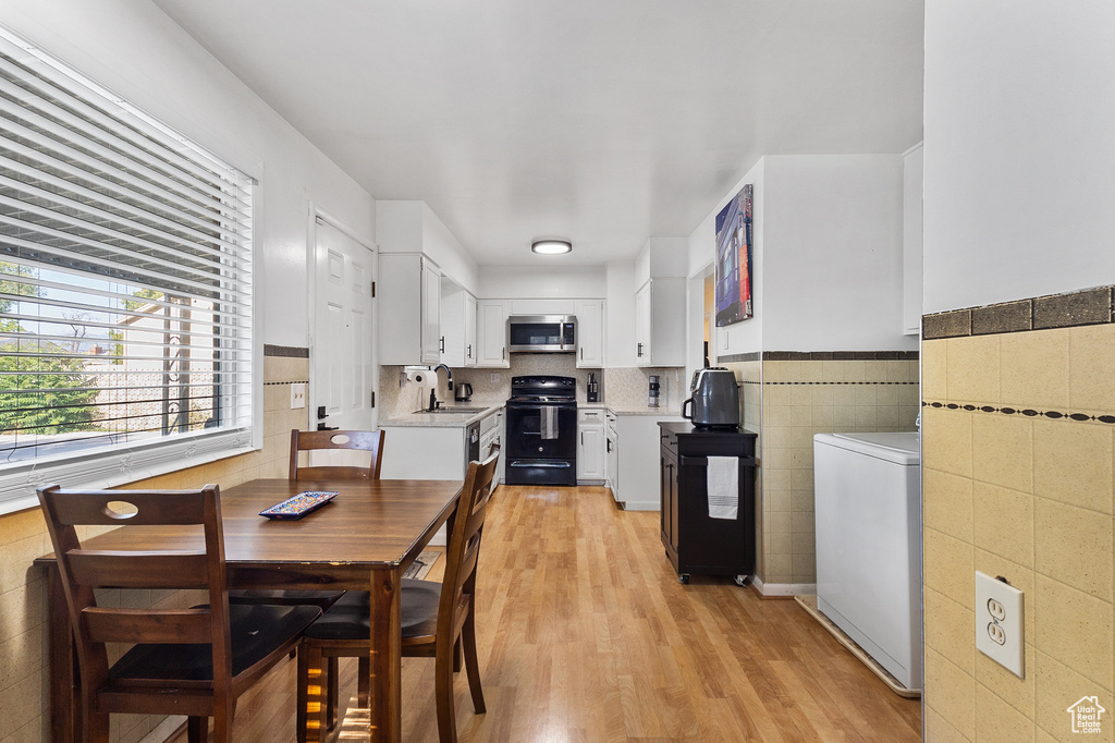 Dining area featuring light wood-style floors, tile walls, washer / dryer, and wainscoting