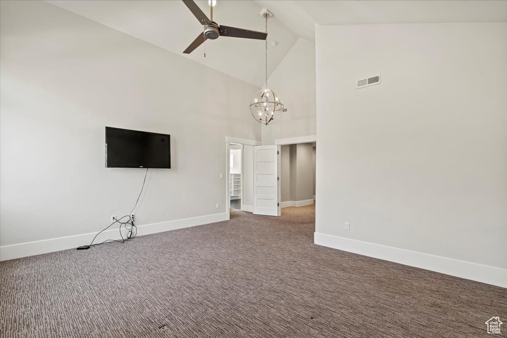 Unfurnished living room with high vaulted ceiling, ceiling fan, carpet floors, and a chandelier