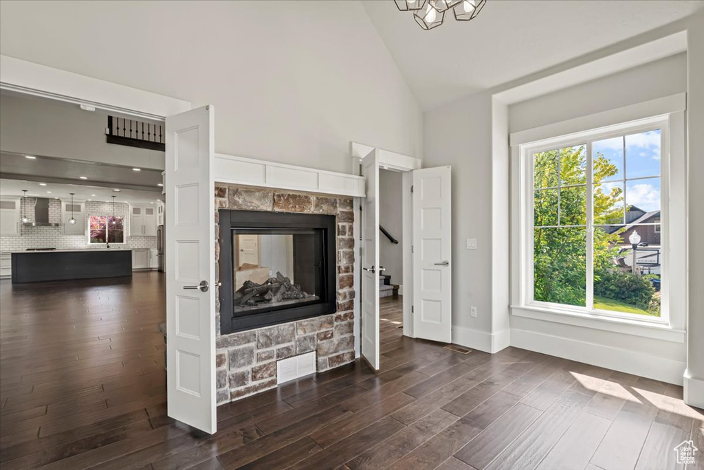 Unfurnished living room with high vaulted ceiling, dark wood-type flooring, a fireplace, and stairs