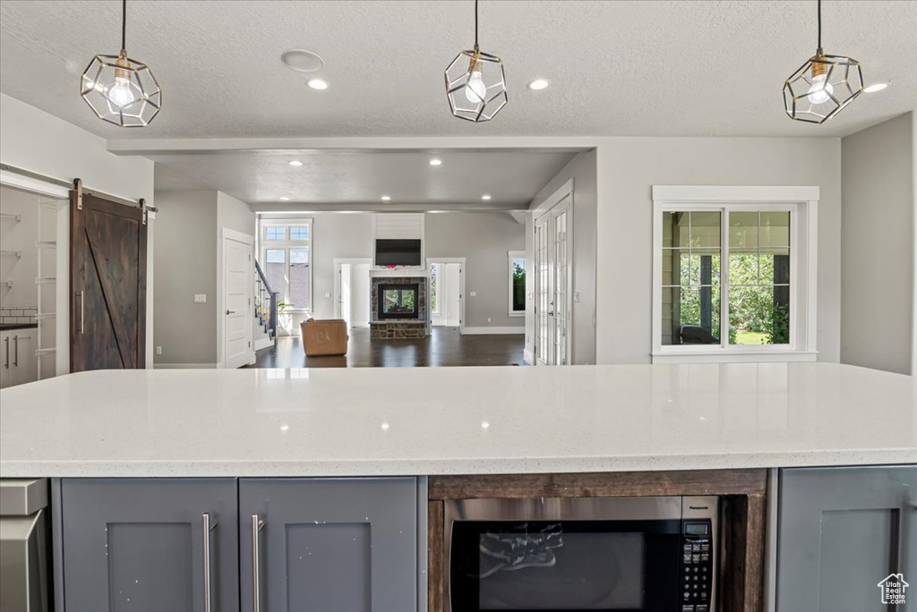 Kitchen with gray cabinets, stainless steel microwave, a barn door, recessed lighting, and a textured ceiling