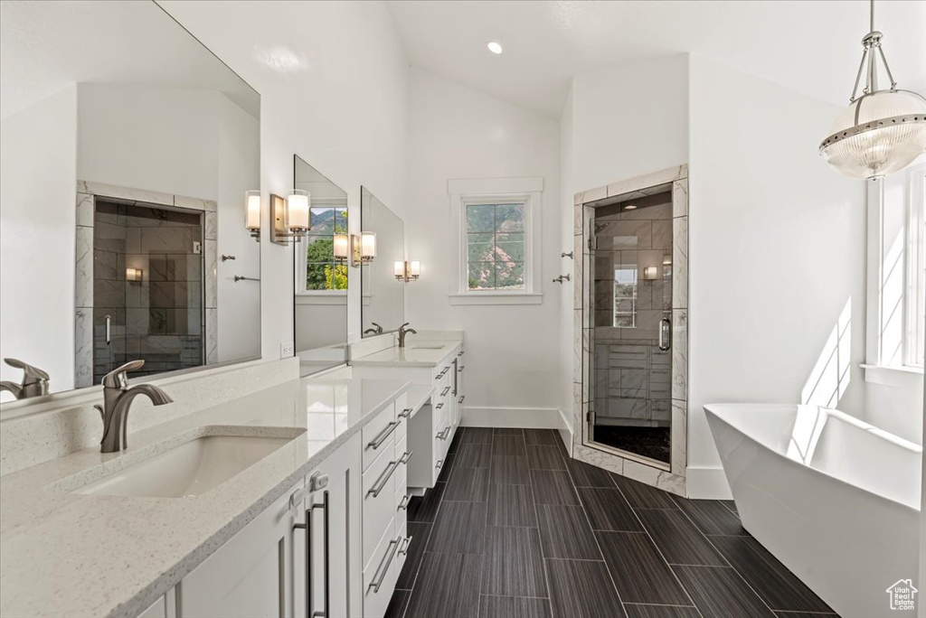 Bathroom featuring double vanity, a freestanding tub, a shower stall, recessed lighting, and vaulted ceiling