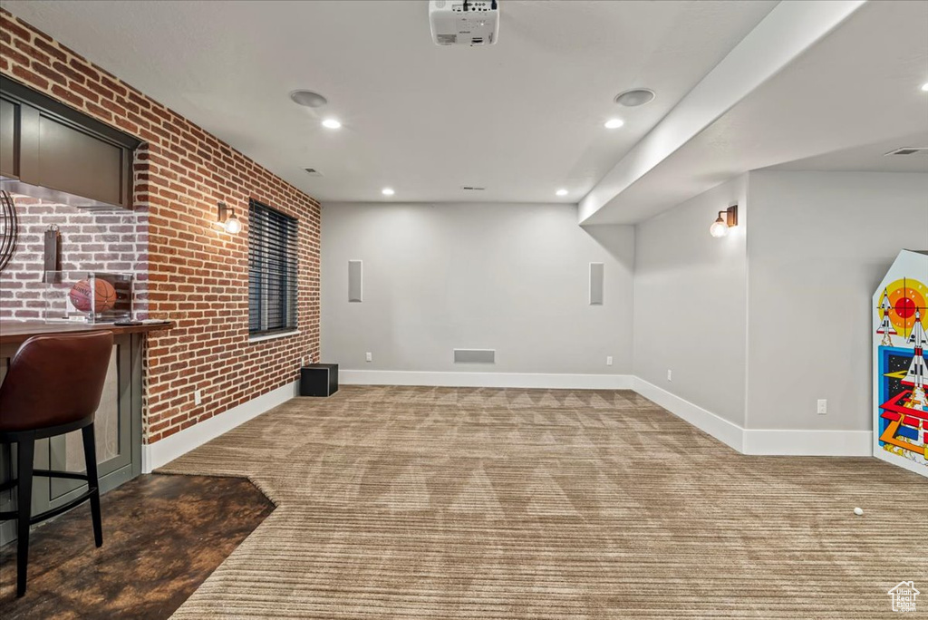 Finished basement featuring carpet floors, brick wall, and recessed lighting