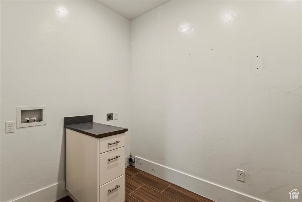 Washroom with electric dryer hookup, hookup for a washing machine, wood tiled floors, and cabinet space