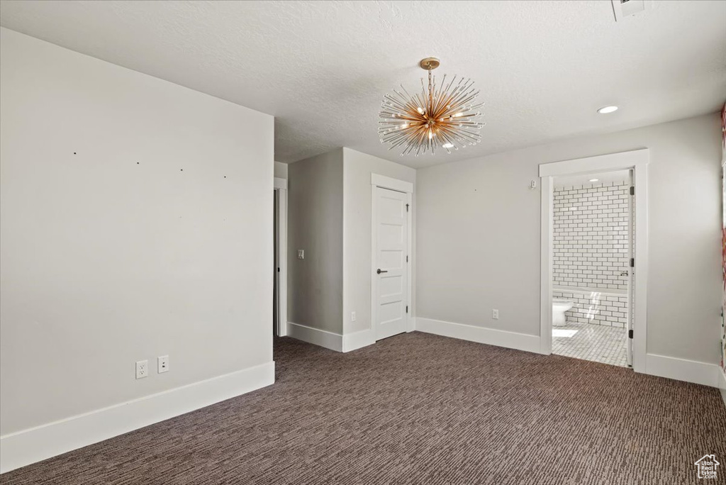 Empty room with a chandelier, dark carpet, and recessed lighting