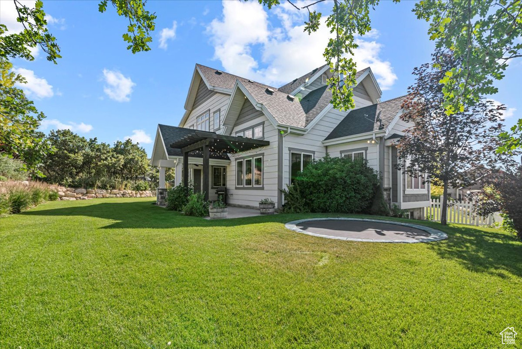 Rear view of house featuring a trampoline, a pergola, a patio, and a shingled roof