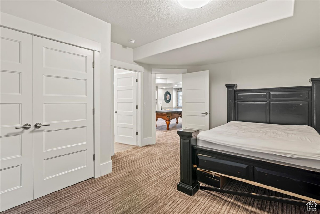 Bedroom with light colored carpet, a closet, and a textured ceiling