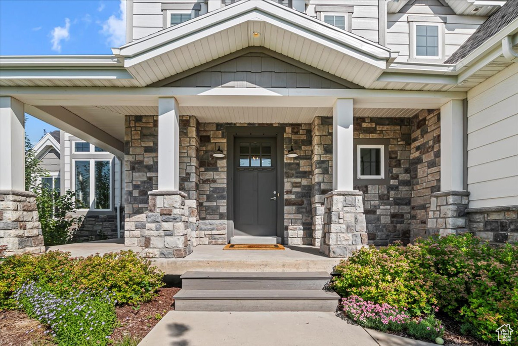 Entrance to property featuring stone siding and covered porch