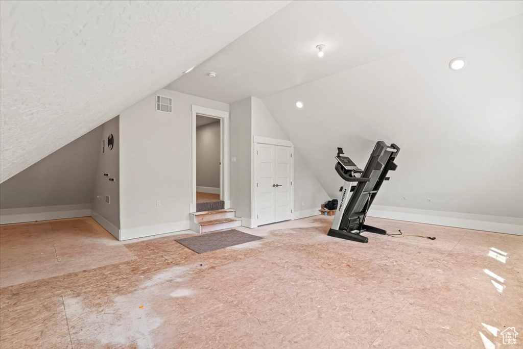 Workout room with lofted ceiling and baseboards
