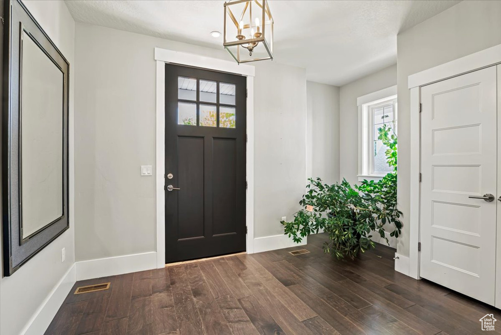 Entrance foyer with wood finished floors and a chandelier
