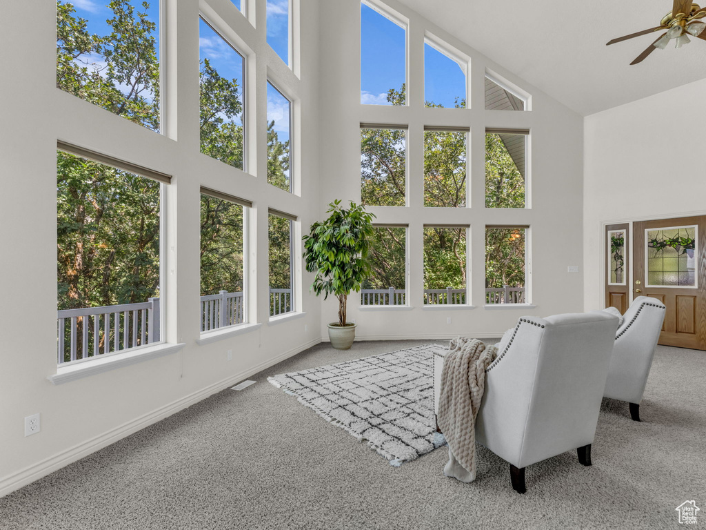 Carpeted living room with high vaulted ceiling and ceiling fan