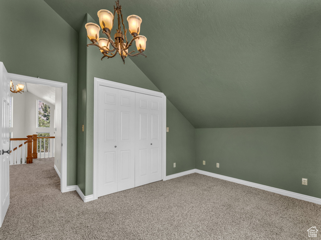 Bonus room featuring vaulted ceiling, a chandelier, and carpet floors