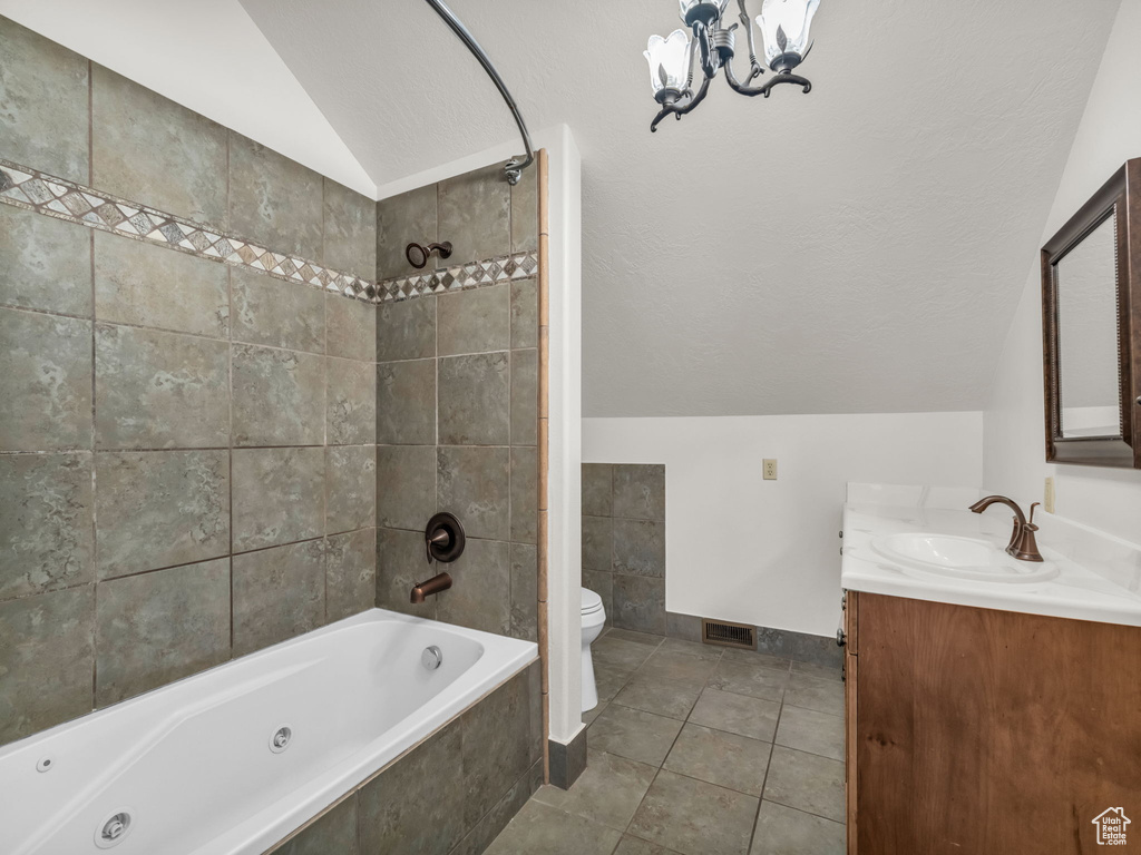 Full bath featuring lofted ceiling, vanity, a combined bath / shower with jetted tub, tile patterned floors, and a chandelier