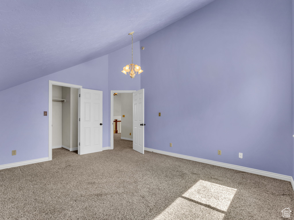 Unfurnished bedroom featuring carpet, a chandelier, and high vaulted ceiling