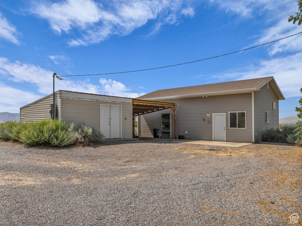 Back of property with an outdoor structure and driveway