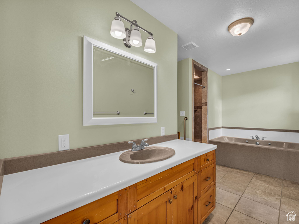 Full bathroom featuring a garden tub, vanity, tile patterned floors, and a shower