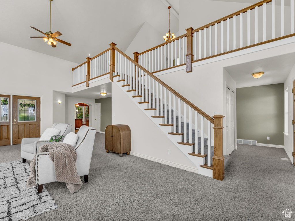 Living room featuring high vaulted ceiling, carpet, stairway, and ceiling fan