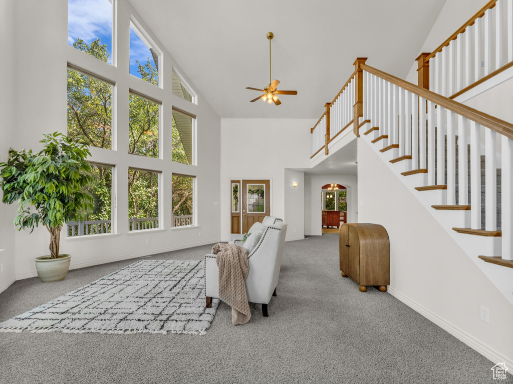 Living area featuring high vaulted ceiling, carpet flooring, plenty of natural light, and a ceiling fan