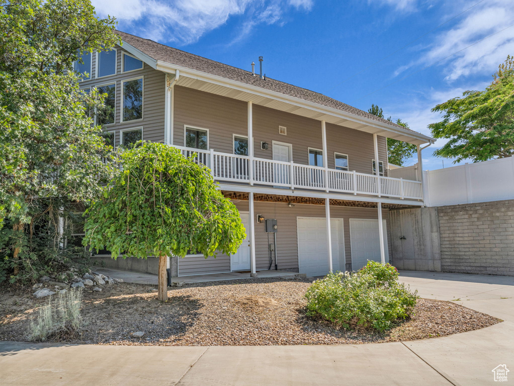 View of front facade with concrete driveway, a garage, and a balcony