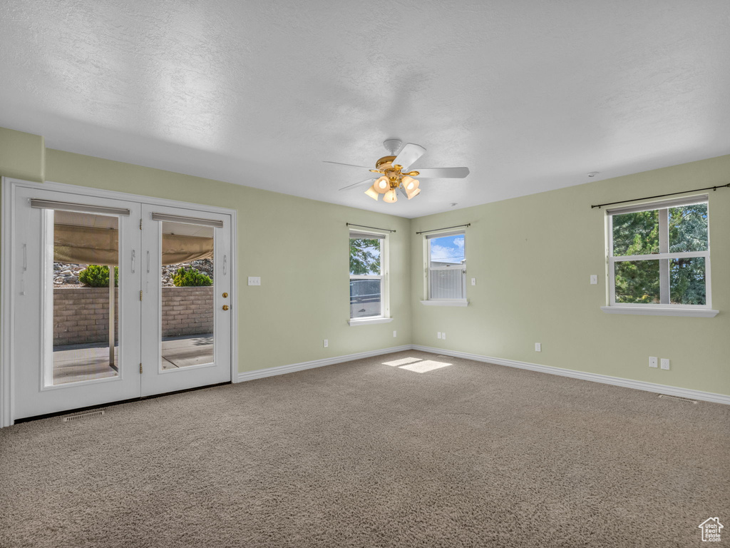 Carpeted spare room with ceiling fan and a textured ceiling