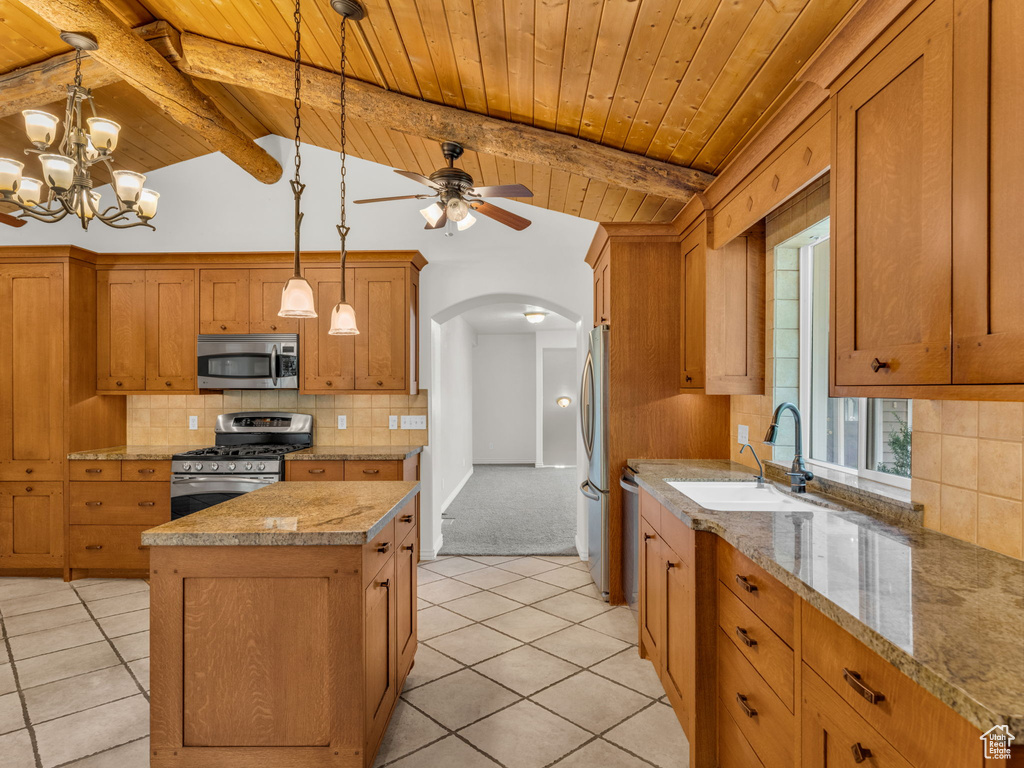 Kitchen with appliances with stainless steel finishes, arched walkways, wood ceiling, a center island, and tasteful backsplash